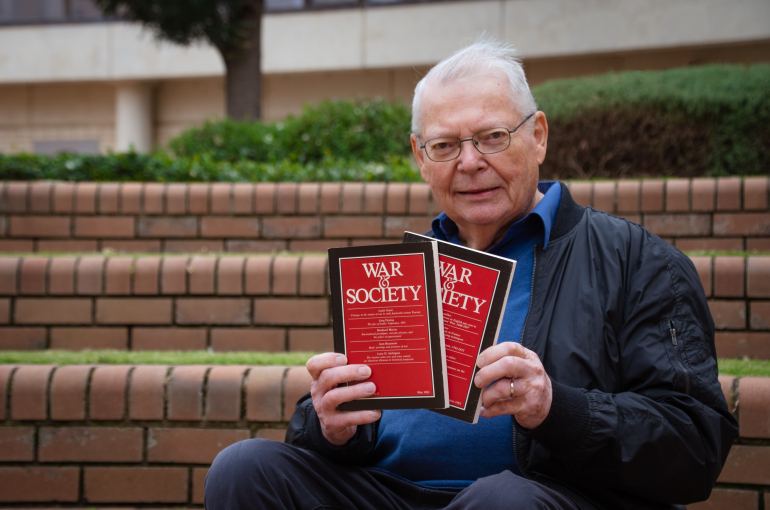 Professor Peter Dennis holds two books titled 'War & Society'