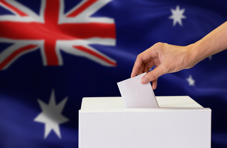 A ballot is placed in a box in front of an Australian flag