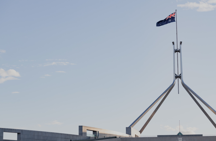 Flag atop Parliament House against a blue sky background. 