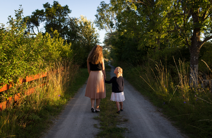 Woman and girl walking on road. 